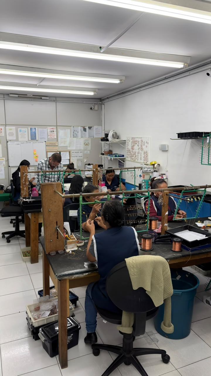 Equipe montando peças em gancheiras no setor de acabamento
